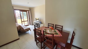 A dining area with a table set for six, a sofa, and a TV in the background. - Condominio Aspen (Nova Petropolis)