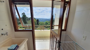 A bathroom with a bathtub, a window, and a view of a balcony with a railing. - Condominio Aspen (Nova Petropolis)