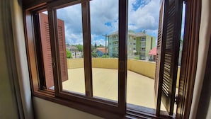 A window with a view of a residential area, including a curved balcony and buildings with balconies. - Condominio Aspen (Nova Petropolis)