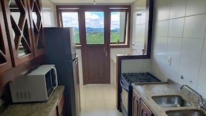 A kitchen with a microwave, stove, and sink. - Condominio Aspen (Nova Petropolis)