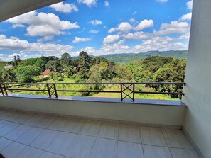 Ein Balkon mit Blick auf eine grüne Landschaft und ferne Hügel.