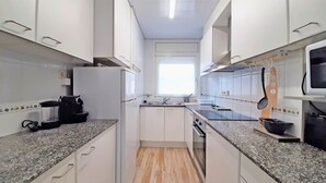 Eine kompakte Küche mit weißen Schränken, Granit Arbeitsplatten, einem eingebauten Backofen und einer Mikrowelle.