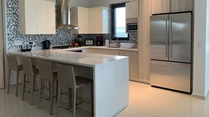 Una cucina moderna con isola centrale, elettrodomestici in acciaio inossidabile e zoccolo in piastrelle.