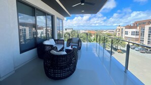 Un balcone con mobili in vimini, ampie finestre e vista sulla città.