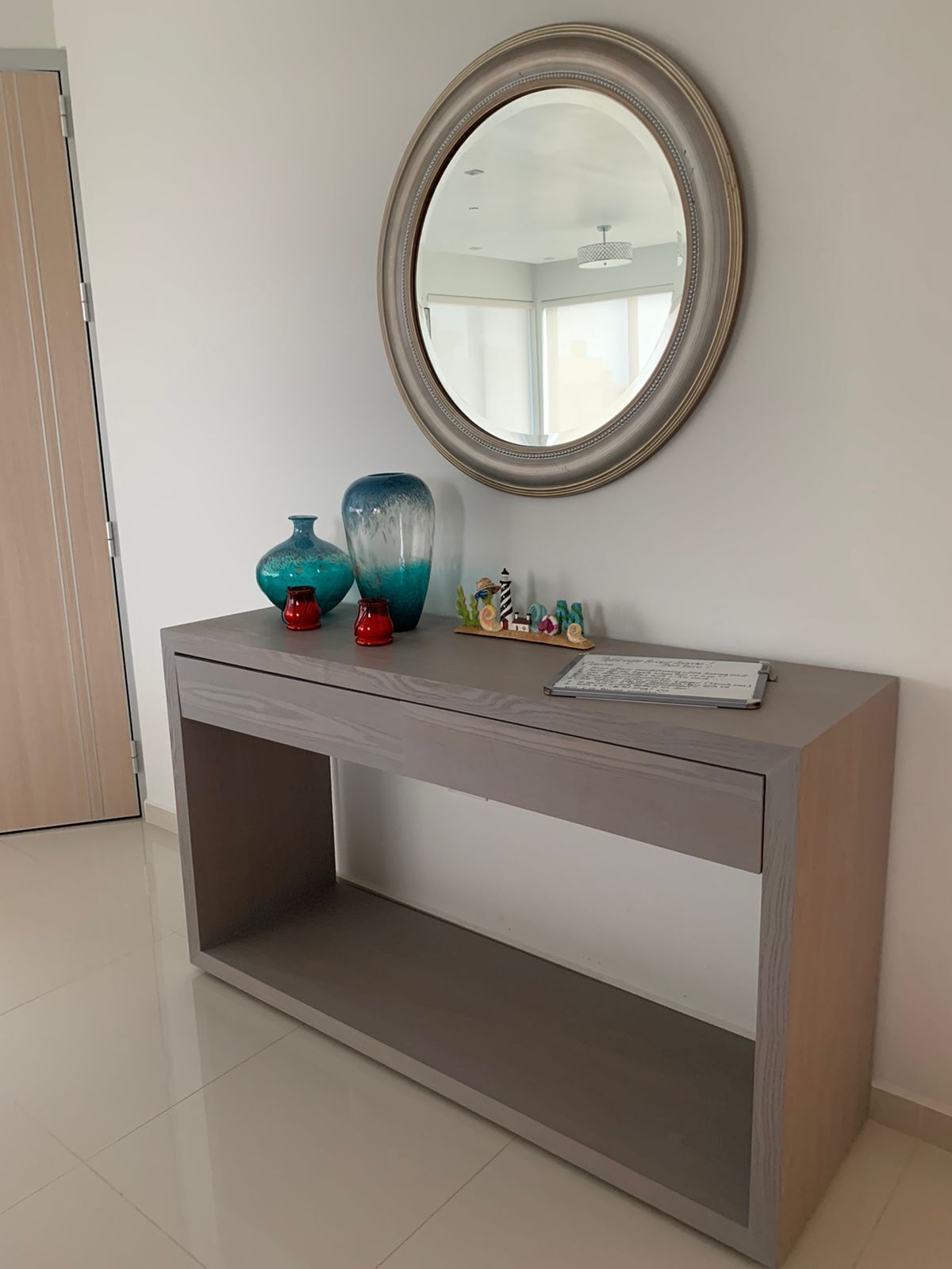 A modern console table with a round mirror, decorative vases, and a small figurine.