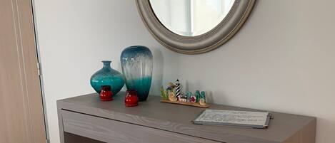 A modern console table with a round mirror, decorative vases, and a small figurine.