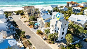 Una zona residenziale sulla costa, con diverse case, vista libera sull'oceano e un parcheggio.