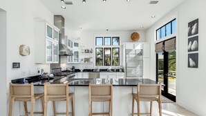 Una cucina moderna con un'isola grande, mobili bianchi e vista sull'esterno.