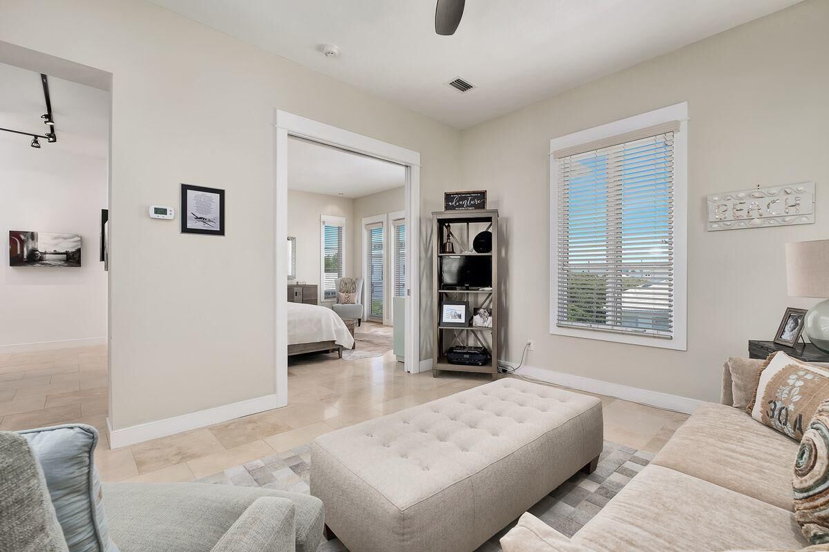 A spacious living room with a large beige sectional sofa, a neutral-toned ottoman, and a modern fireplace.