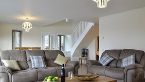 Ein geräumiges Wohnzimmer mit zwei grauen Sofas, einem Holztisch und einer Treppe, die in den oberen Bereich führt.