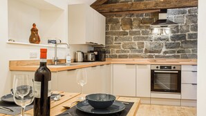 Een moderne keuken met een stenen muur, houten balken en een inbouwoven.