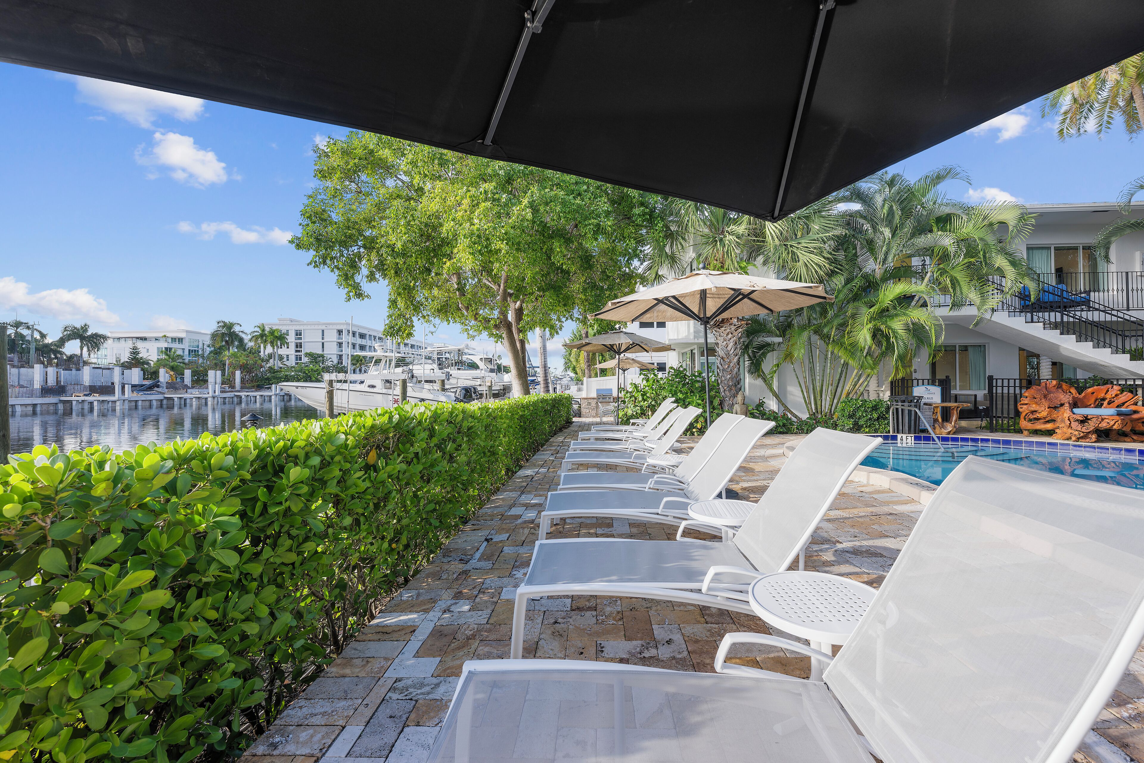 Zona junto a la piscina con sillones de descanso, una piscina y vistas al puerto deportivo.