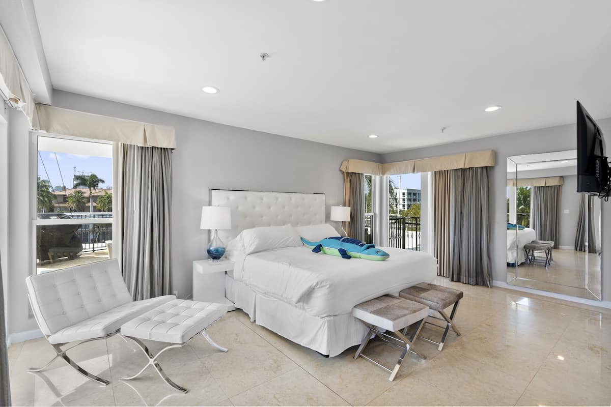 Quarto de hotel moderno com cama grande, área de estar, televisão e varanda com vista.