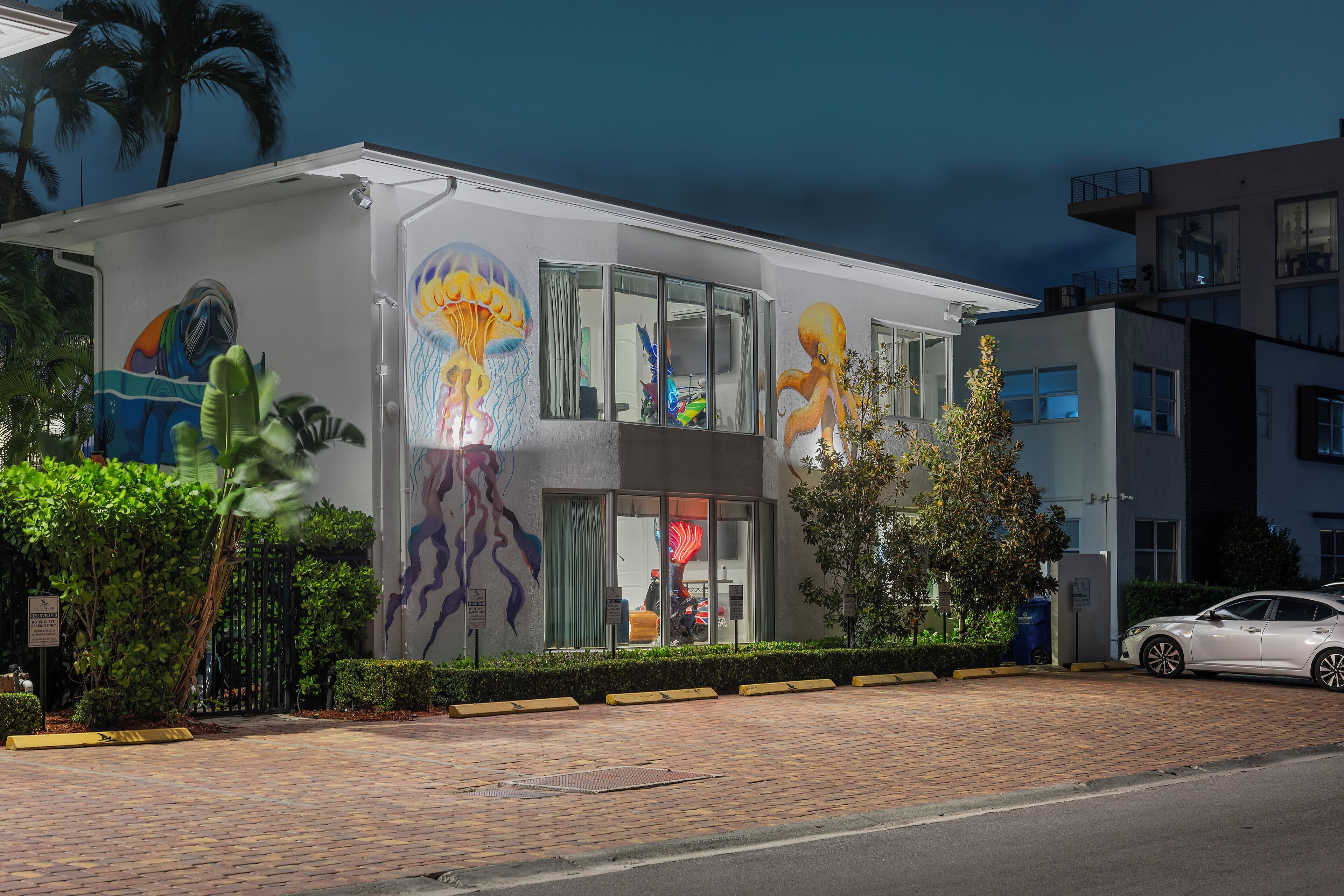 Un bâtiment moderne doté de grandes fenêtres et d’une fresque représentant une faune marine colorée sur la façade.