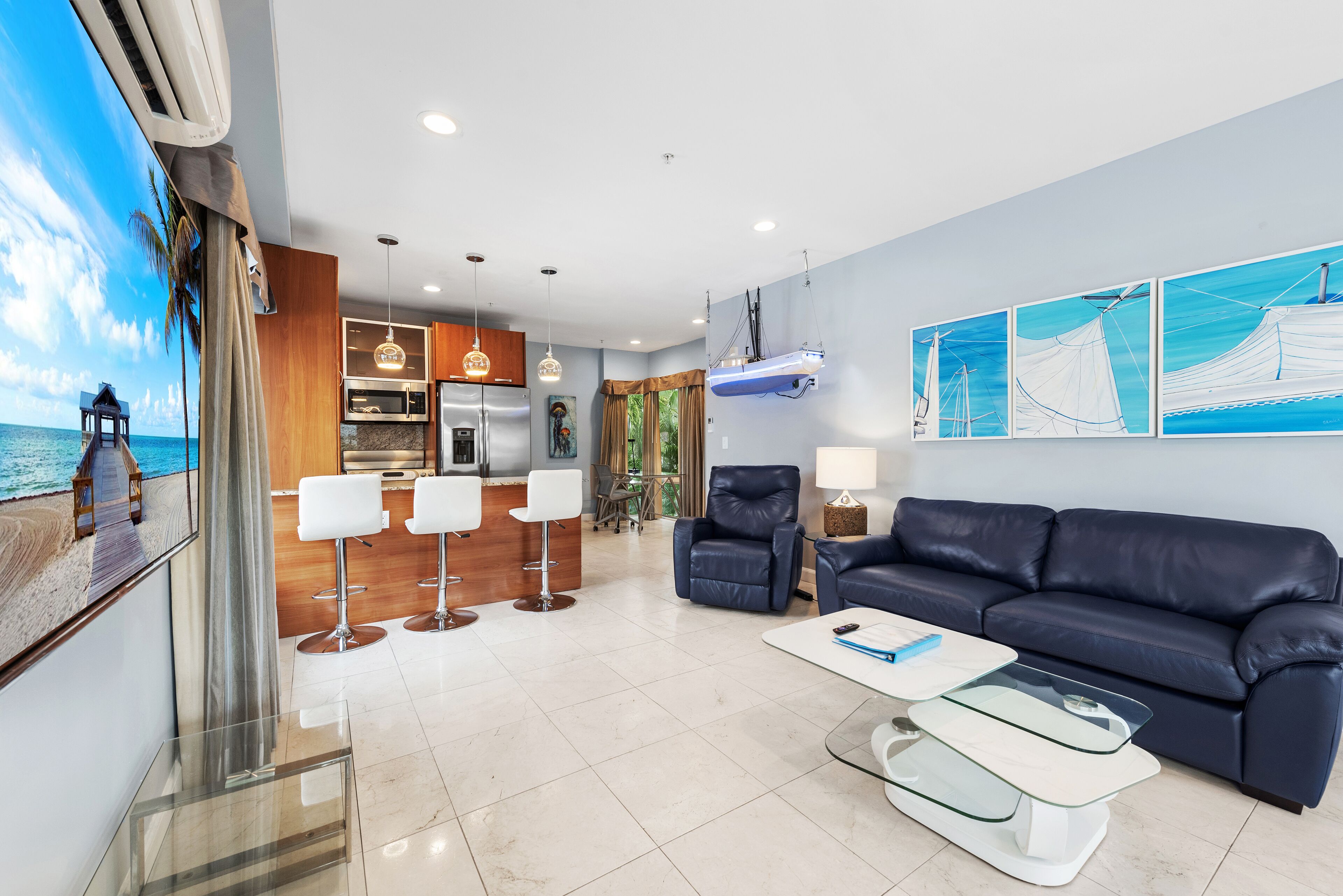A modern living room with a sofa, a coffee table, and a dining area with bar stools.