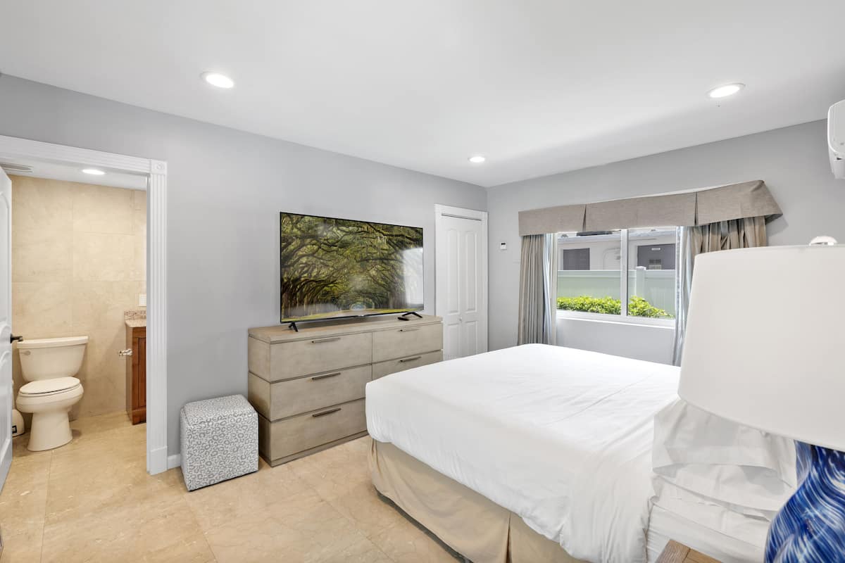 Quarto com cama, cômoda e uma grande janela.