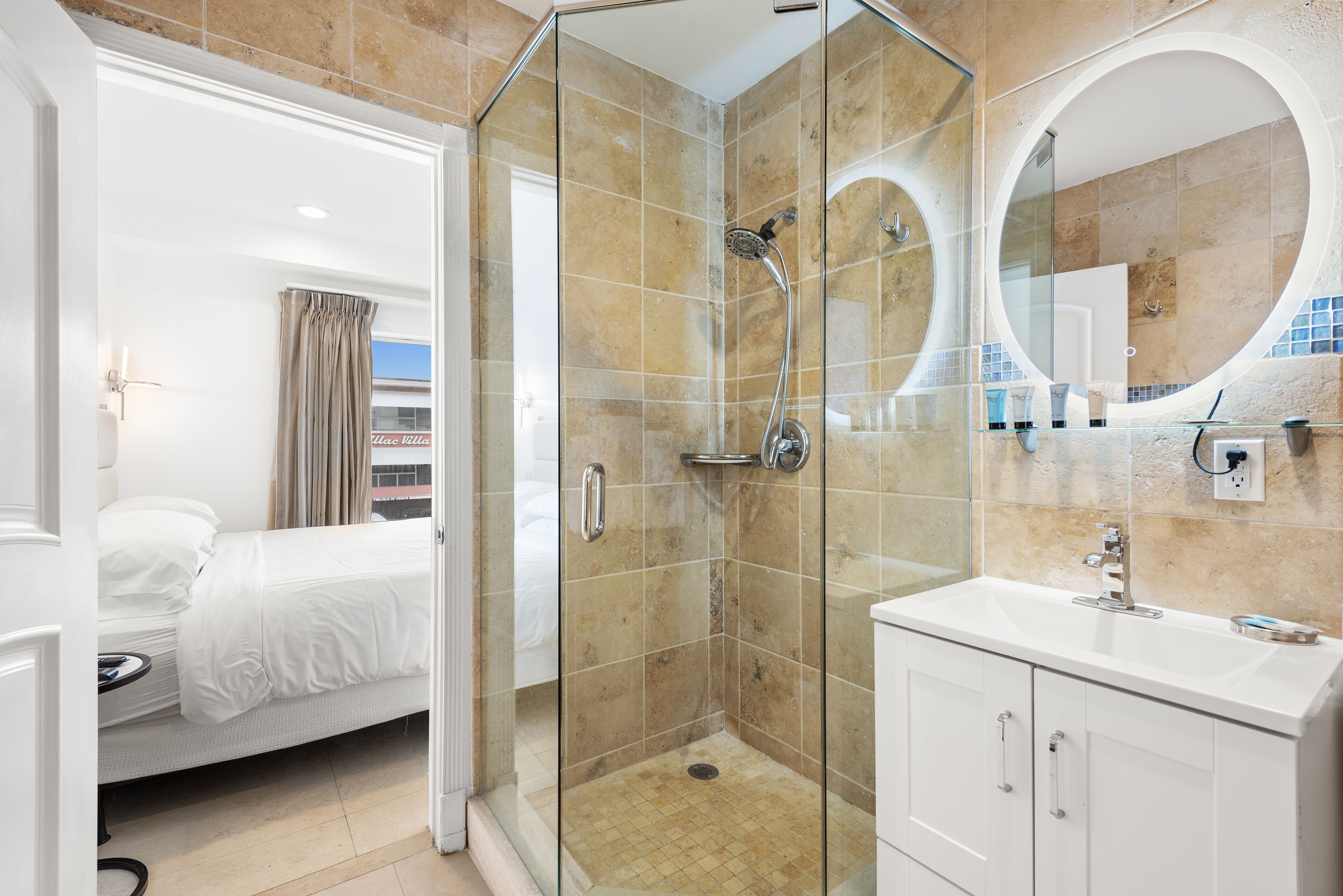 A modern bathroom with a glass-enclosed shower, a large mirror, and a white sink.