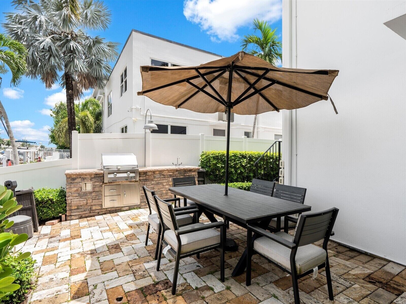 Une terrasse extérieure équipée d’un barbecue, d’une table à manger et de chaises.