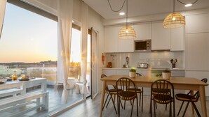 A modern kitchen with a dining area, large windows, and a view of the cityscape. - Sunny Penthouse - Modern & Premium Apartment (Peniche)