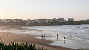 A beach with surfers and waves, houses in the background, and a clear sky. - Sunny Penthouse - Modern & Premium Apartment (Peniche)