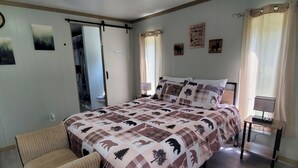 A bedroom with a bed, a chair, a desk, and a window with curtains. - Charlie's Woodside Getaway-4 miles from the Dells! (Lyndon Station)