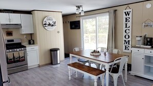 A kitchen with a dining area, a stove, a trash can, and a coffee station. - Charlie's Woodside Getaway-4 miles from the Dells! (Lyndon Station)