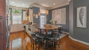 A kitchen with a central island, bar stools, and a decorative wall panel. - Coastal Condo w/ Pool, Balconies, Sundeck & Boat Slip - Near Beach (Corpus Christi)