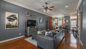A modern living room with a grey sofa, a flat-screen TV, and artwork on the walls. - Coastal Condo w/ Pool, Balconies, Sundeck & Boat Slip - Near Beach (Corpus Christi)