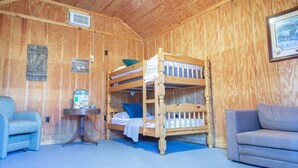 A wooden room with a bunk bed, a small table with a lamp, a chair, and a sofa. - 1 rm cabin, shared bth house, at Kick Back Ranch. (Ramer)