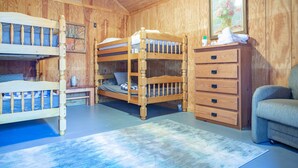 A wooden room with bunk beds, a dresser, a chair, and a painting on the wall. - 1 rm cabin, shared bth house, at Kick Back Ranch. (Ramer)