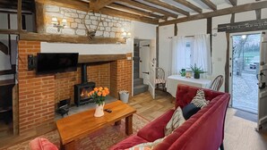 Un salon avec une cheminée, un canapé rouge, une table basse en bois et un téléviseur fixé au mur.
