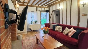Un salon chaleureux avec un canapé rouge, une table basse en bois et un téléviseur fixé au mur.