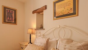 A bedroom with a bed, pillows, a nightstand, a lamp, and two framed artworks on the wall. - A relaxing, rural retreat for two. (Wrelton, near Pickering)