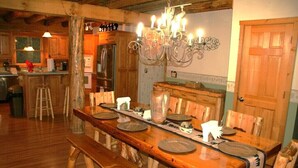 A wooden dining table with chairs, a chandelier, and a wooden bench.