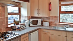 Une cuisine avec des meubles de rangement en bois, un four à micro-ondes, un grille-pain, un évier et une cuisinière.