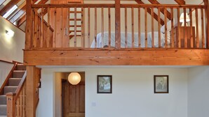 Une chambre à coucher aménagée en mezzanine, avec un escalier en bois, un lit, une petite table et deux tableaux encadrés au mur.