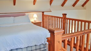 Une chambre à coucher avec une tête de lit en bois, une table de chevet avec une lampe et une couverture à carreaux sur le lit.