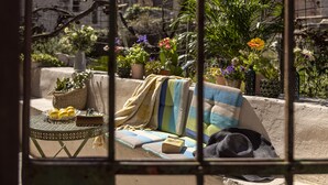 Una zona relax all'aperto con tavolo, cuscini e piante in vaso.