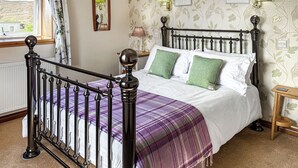 A bed with a headboard, a window with curtains, a wall with framed pictures, and a bedside lamp. - 1 bedroom accommodation in Leverburgh, Isle of Harris (Leverburgh, Isle of Harris)