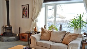 A cozy living room with a sofa, a wooden coffee table, a fireplace, and a window with a view of a snowy landscape. - 3 bedroom accommodation in Kirkby Stephen (Kirkby Stephen)