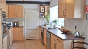 A kitchen with wooden cabinets, a dishwasher, a toaster, and a sink. - 3 bedroom accommodation in Kirkby Stephen (Kirkby Stephen)