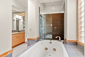 A modern bathroom with a large bathtub, a glass-enclosed shower, and wooden cabinetry. - Unique Seattle Gem: 5BR + 3.5BA w/ lake & mountain views, AC, close to transit (Seattle)