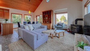 Ein geräumiges Wohnzimmer mit einem großen, grauen Ecksofa, Holzboden und einer integrierten Bücherreol.