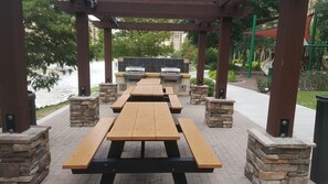 Un patio exterior con mesas de picnic y parrillas.