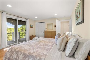 Quarto com cama grande, guarda-roupa, penteadeira e porta de vidro corria para uma varanda.