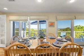 A dining area with a view of the sea, a table set for four, and a large window with a view of the landscape.