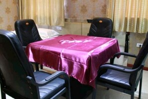 A dining area with a table covered by a red tablecloth, four black chairs, and a window with curtains. - Holiday Yizhan Express Motel (Mudanjiang)