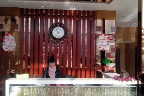 A reception desk with a clock, decorative wall panels, and a sign.