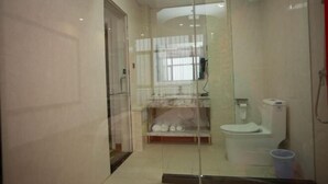 A bathroom with a glass partition, a toilet, a sink, and a shower area.
