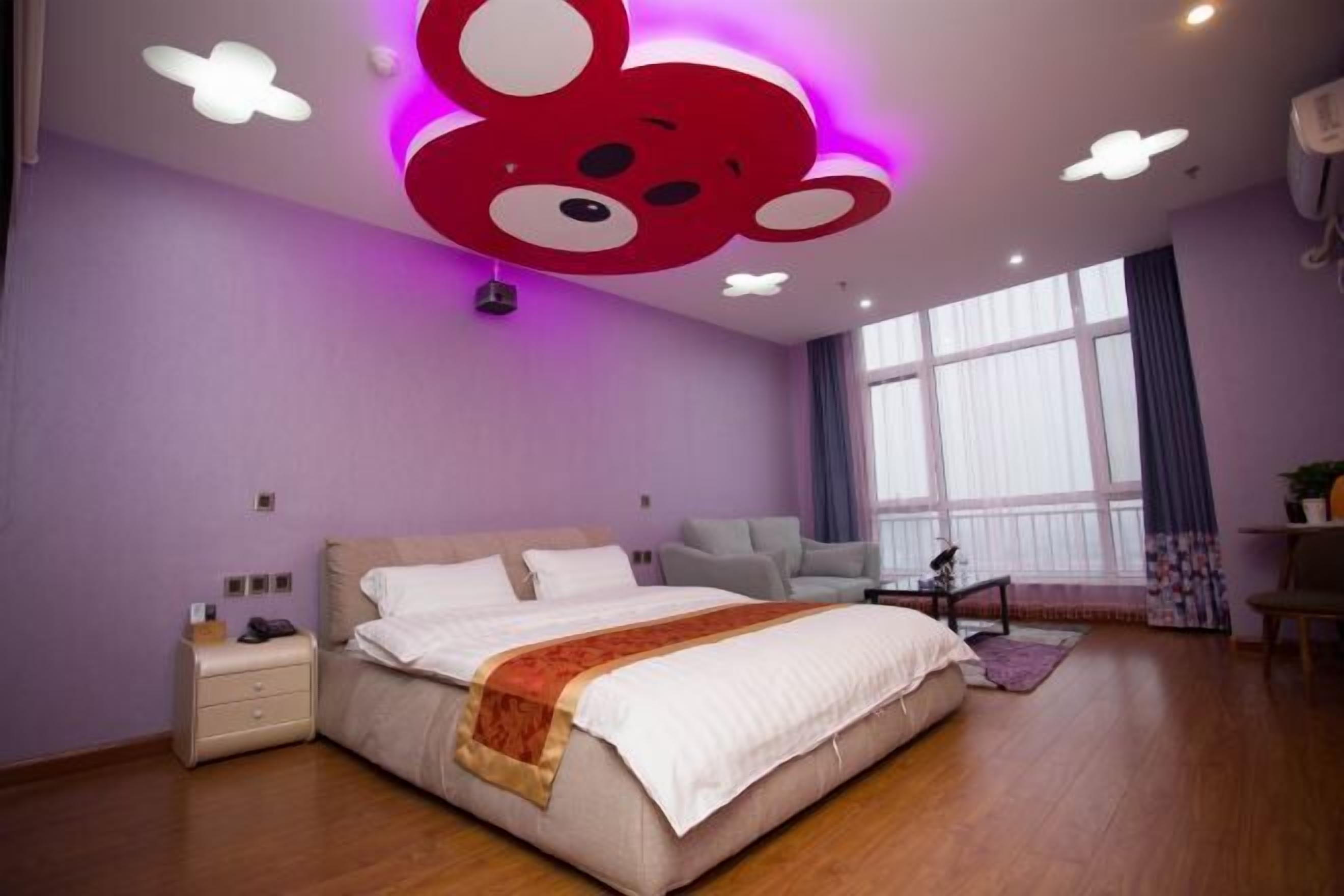 Een slaapkamer met een bed, nachtkastjes, een bureau en een raam.